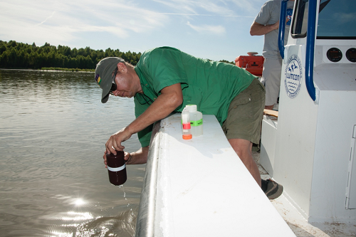 Research collecting water samples from a boat.
