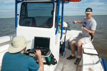 Researchers on a boat collecting data using an instrument.